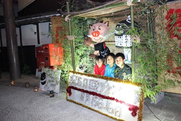 イノシシの作り物とデカボーと書かれた黒い作り物の前で3人の子供たちが並んでいる写真