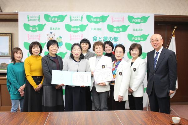 篠山ストーリーテリングの会の賞状を持った女性の皆さんと市長で集合写真