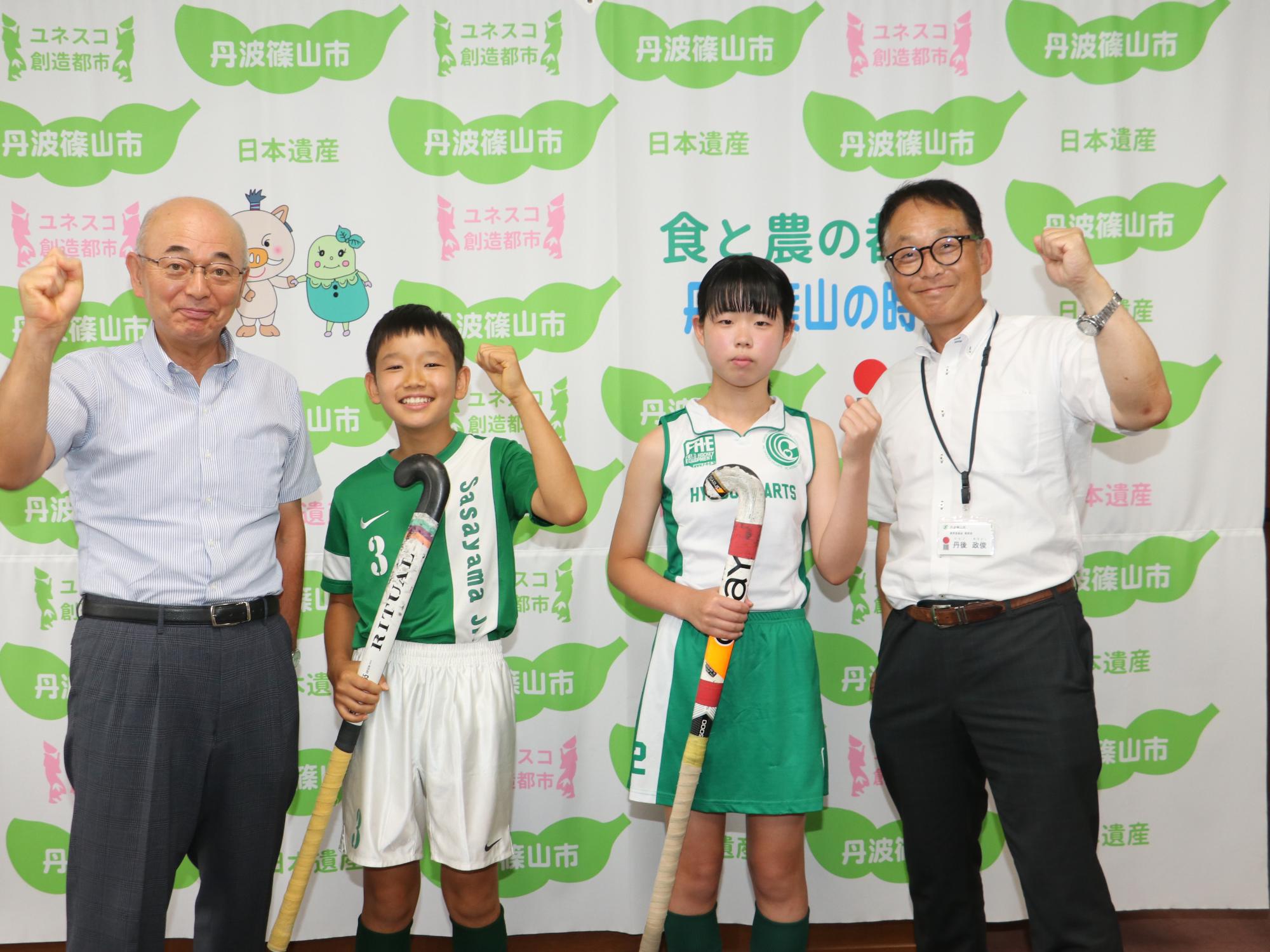 市長と教育長、ホッケーをラケットを持ったこどもたちとの記念撮影