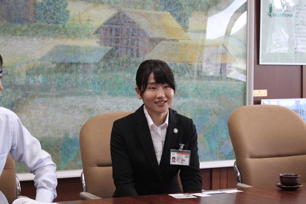 テーブルに並べられた5枚の名刺と席に座っている中西 美加さんの写真