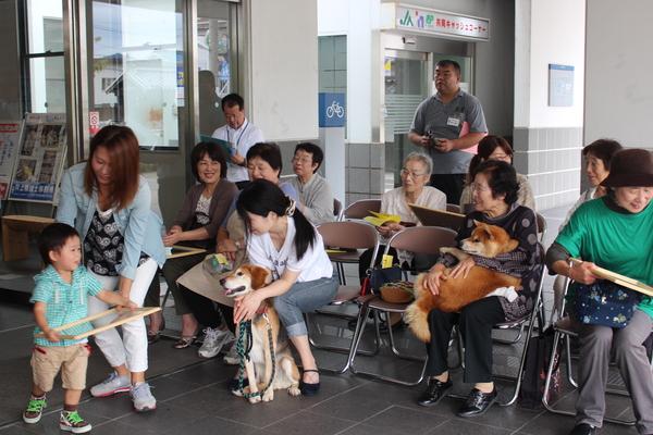 子供が持っている表彰状を母親が落ちないように一緒に持っている、その様子を他の表彰者が見守っている写真