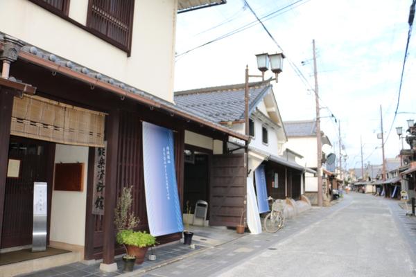 奥には二階建ての日本家屋が3軒並んでいて手前に道路が映っている写真
