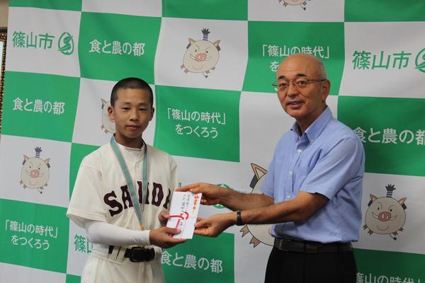 市長とピッチャーの萱野 咲也さんが目録を手に持っている写真
