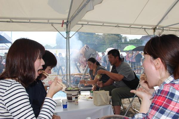 テントの中の飲食コーナーで七輪で肉を焼いて食べている写真