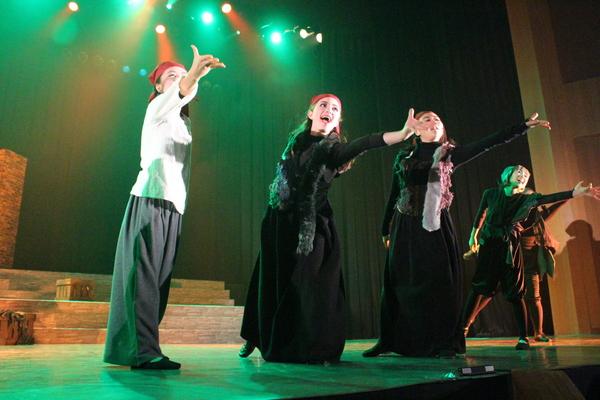 手を前にして笑顔で踊っている5名の方に緑色のライトが当たっている写真