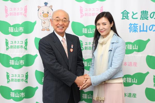 香港の女優、モデルとして映画などで活躍中の龍媚（LONGMEI）さんと、市長が笑顔で両手を握っている写真