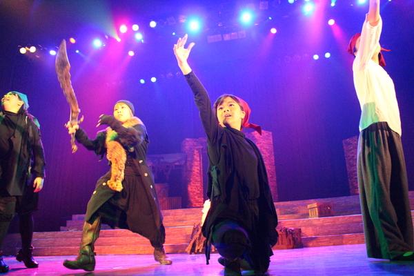 右手を前に出して踊っている出演者に赤赤としたライトが当たっている写真