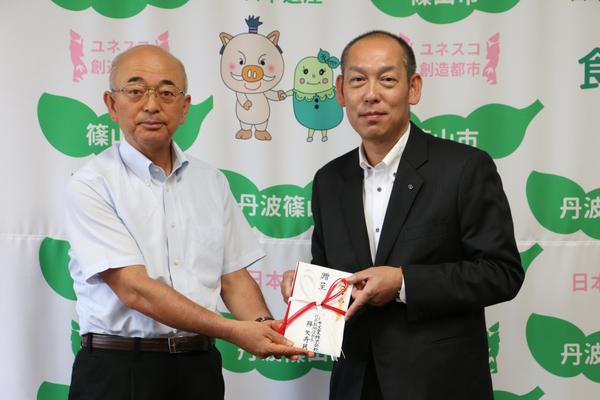 フルヤ工業株式会社の代表取締役社長の降矢 寿民さんと市長が、一緒に寄付金の封筒を持っている写真