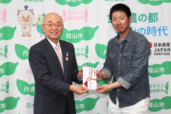 平井 駿也さんと市長でお祝いの封筒を持って、記念写真