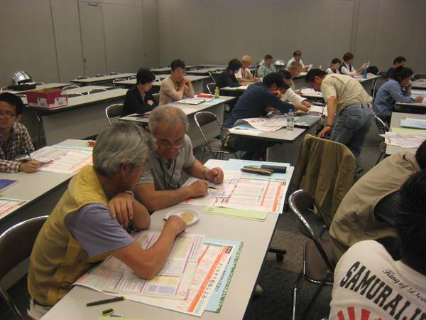 白い平たい皿の上にのっている米を触って凝視している男性2名の写真