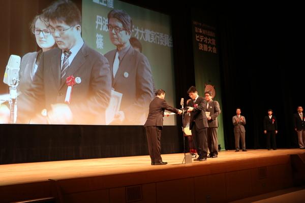 舞台上で気軽にチャレンジ部門の表彰が行われており、舞台上の大きなスクリーンにも表彰の映像が映し出されている写真