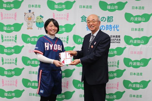 戸倉 紗希さんと市長が目録を手に持ち笑顔で記念撮影写真