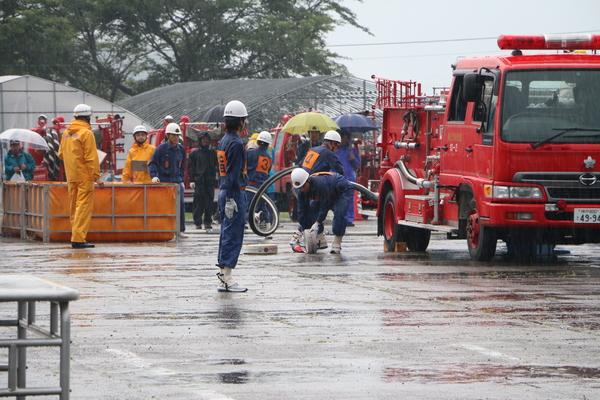 消防車から団員達がホースを出している写真