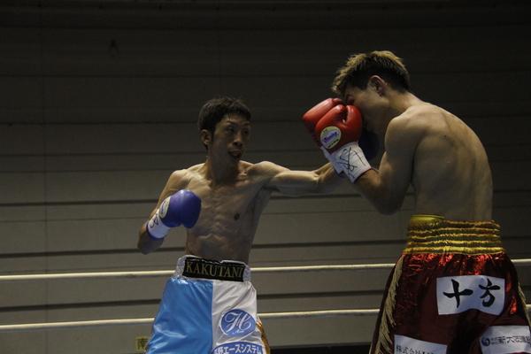 角谷 淳志選手が相手選手の顔面にパンチをしようとしているのを相手選手がグローブで防御している写真