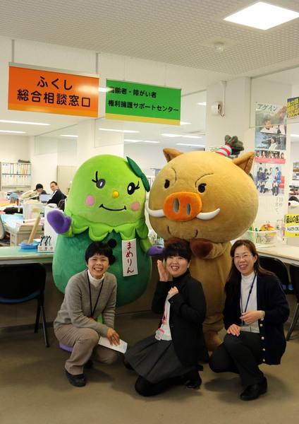 「高齢者・障がい者権利擁護サポートセンター」の窓口の前で篠山市のゆるキャラ「まめりん」「まるいの」と女性職員3名と一緒に記念撮影している写真