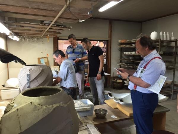 窯元で作業している様子を外国人の男性3人が見学している写真