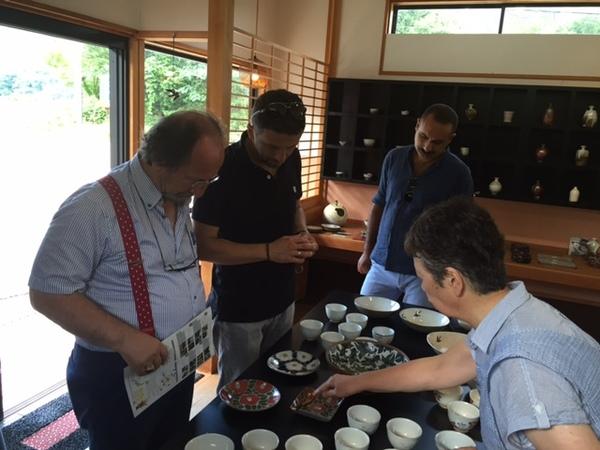 机に並べられた陶芸作品を見ながら外国人の方達が説明を聞いている写真