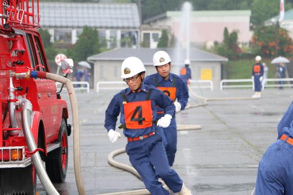 団員2名が訓練で消防車の前を走っている写真