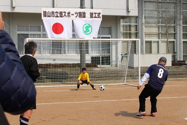 市長がゴールを狙って蹴っており、ゴールキーパーが飛んでくるボールを掴もうと構えている様子の写真