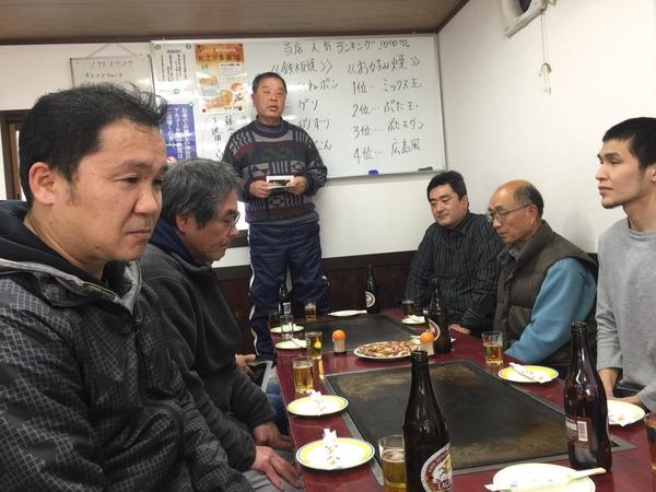 お好み焼き屋さんで、応援する会の粟野会長が立って話をしている写真