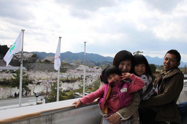 市長室のバルコニーで、桜をバックに立つ、笑顔の家族4人の集合写真