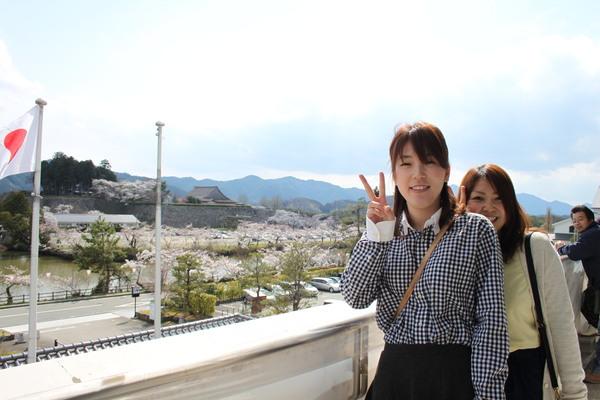 市長室のバルコニーで、笑顔でピースサインをする女性2名の写真