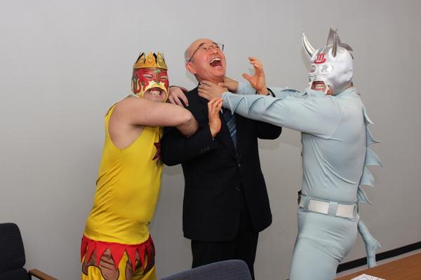 市長がニューワールドに首を絞められ、タコヤキ―ダーから腕も掴まれて技をかけられており、市長が叫んでいるようなふりをしている様子の写真