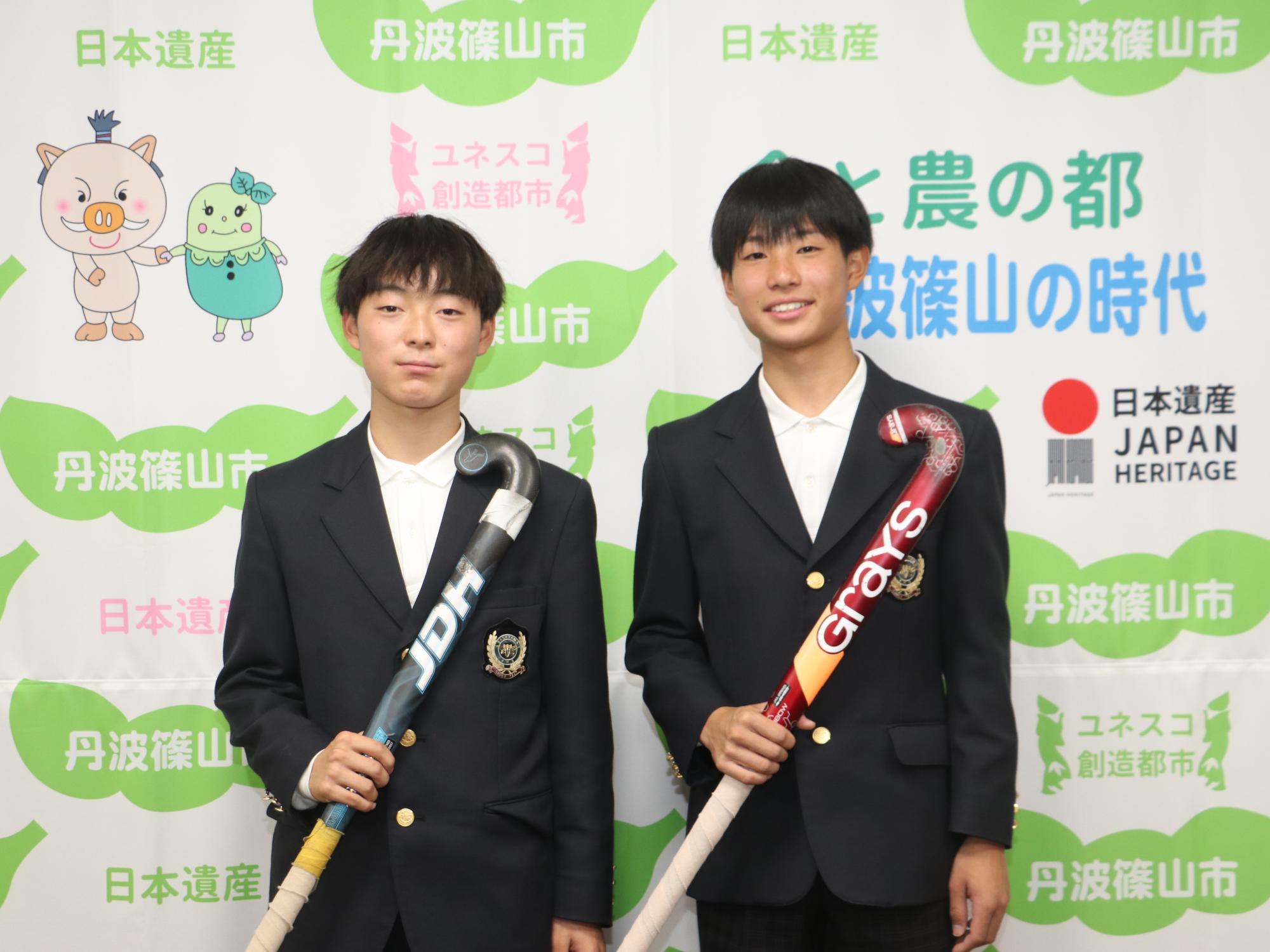 ホッケーのスティックを手に持った田中さんと中井さんの記念撮影