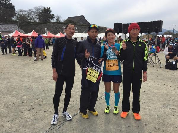 1名の女性ランナーと3名の男性ランナーが横に並び、親指を立ててポーズをとっている写真