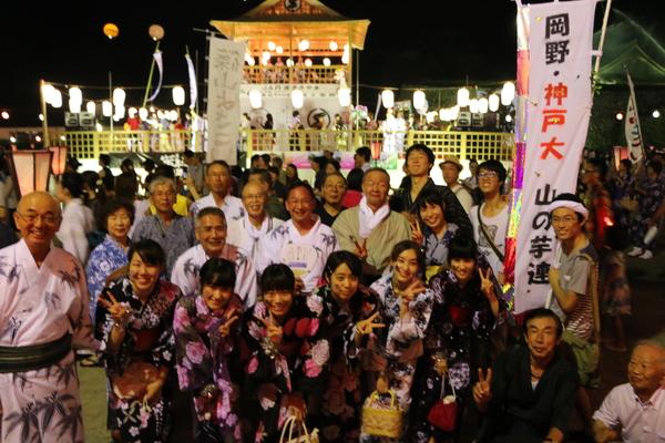 ヤグラで踊る人をバックに市長と浴衣姿の人々の記念写真