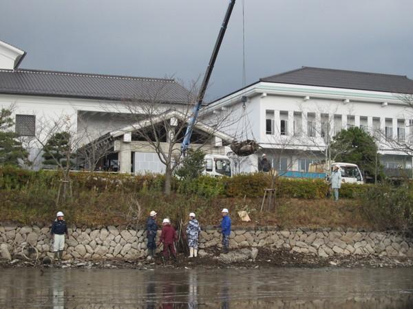 作業着を着た作業者がクレーン車でゴミを回収をしている写真