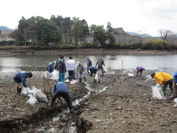 北堀の池付近で雨靴や作業着で、ごみ回収をしている写真
