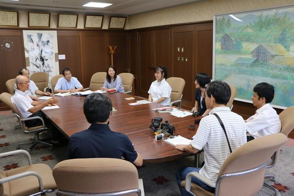 応接室の会議テーブルに座る上野さんと、市長、関係者の写真