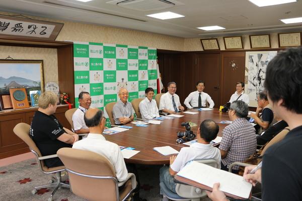 丸テーブルに角谷 淳志（かくたに あつし）選手、関係者、市長などが座り、談笑をしている写真