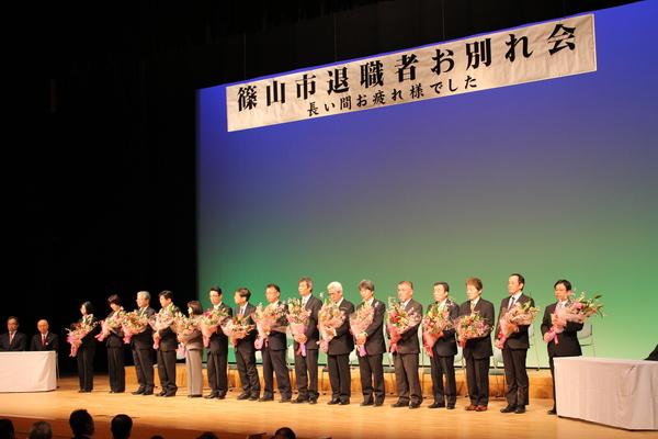 壇上に篠山市退職者が花束を持って、一列に並んでいる写真