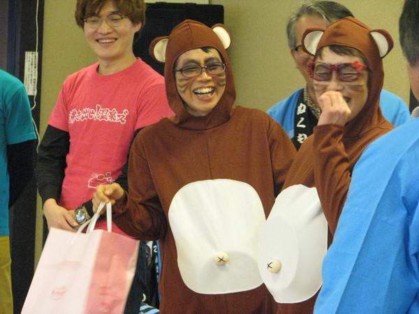 目がねをかけ顔にひげを描き、たぬきのコスプレをした女性二人が笑顔で写っている様子の写真