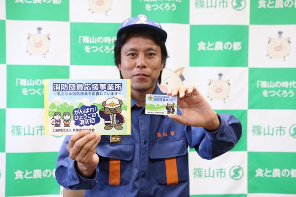 消防団員が消防団員応援事業所ポスターと消防団員カードを持っている写真
