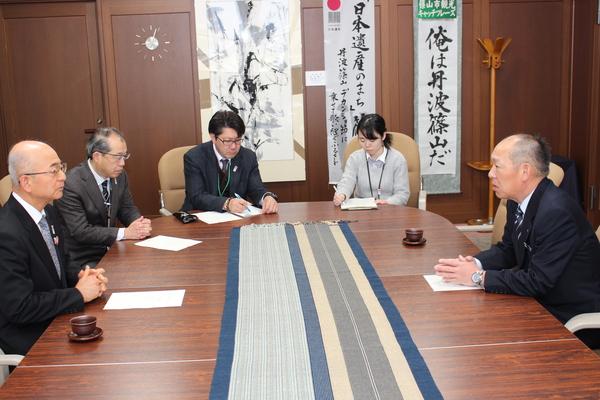 降矢 寿民さんが市長と真剣にお話ししていて、周りでは男性と女性の方が話の内容をメモしている写真