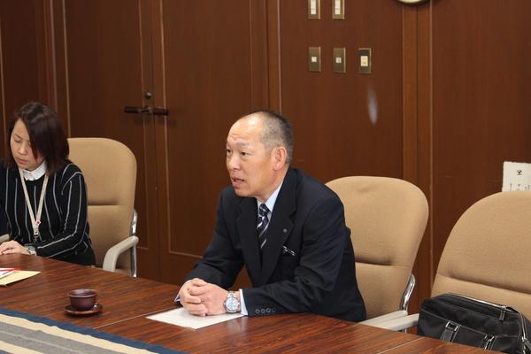 社長の降矢 寿民さんがお話しをして、隣では女性がお話しを聞いている写真