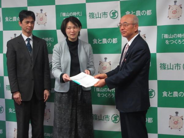 篠山環境みらい会議エネルギー部会の代表の方2人が市長に提言書を渡している写真
