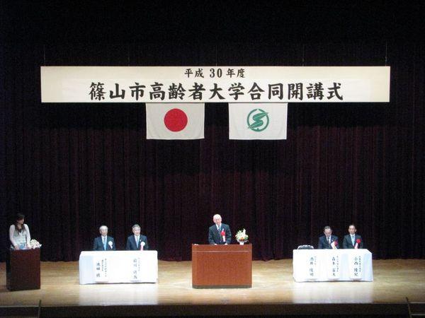 篠山市高齢者大学合同開講式が開催され舞台の上で男性の方がお話されている写真