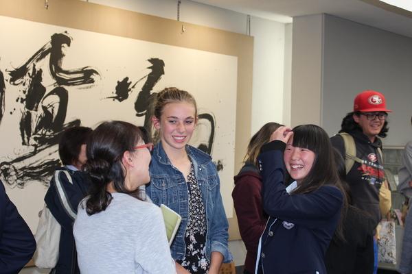 外国人女性と、制服を着た女子学生が笑顔で話している写真