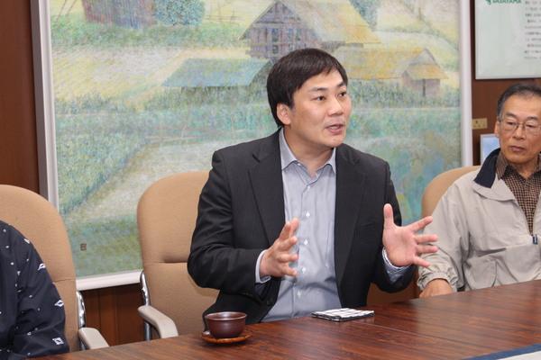 田中 美央さんが手の動きをつけて話をしている様子を見ている父親の写真