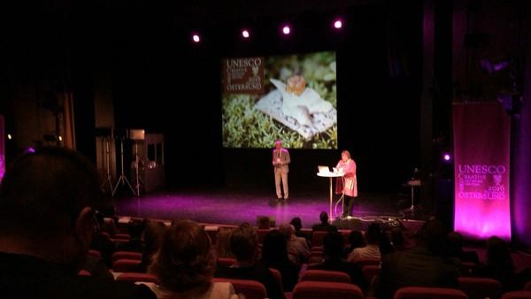 エステルスンド市長が舞台の上でピンク色のライトに照らされている写真