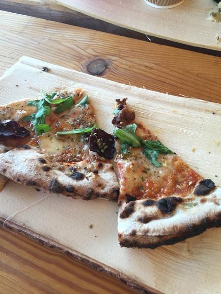 木のお皿にピザがのっている写真