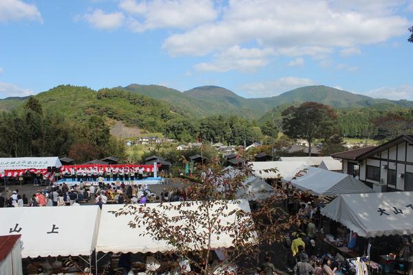 青空の下、山々に囲まれている景色の中で行われている大山の市民農園で収穫祭の写真