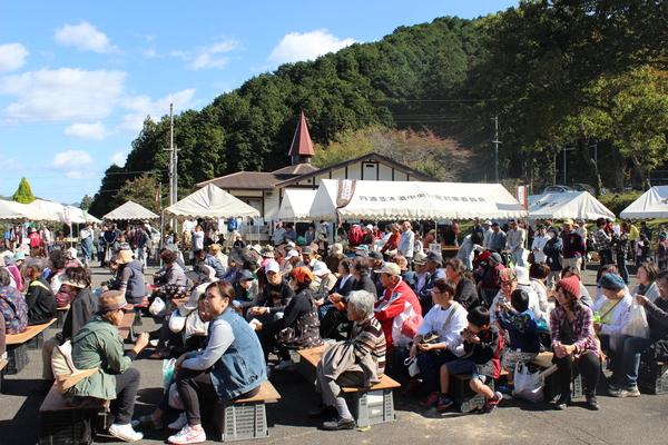 大山荘の里市民農園収穫祭でテントと椅子が設置されたており、テントを見て回る人々や椅子でくつろぐ人々の写真