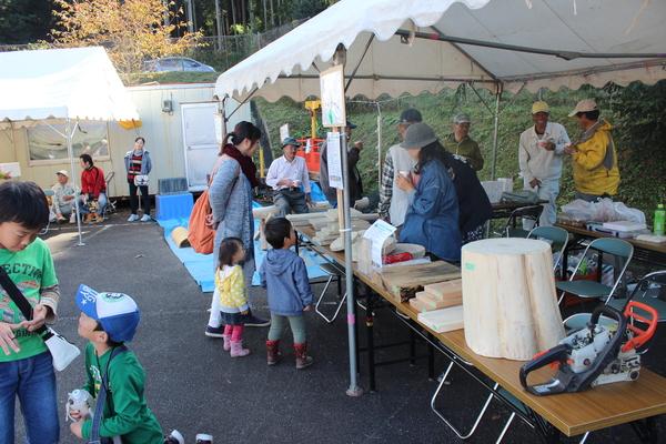 テントに展示されている木材を見て回る親子連れたちの写真