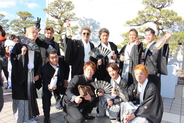 袴やスーツを着た新成人の男性10名がセンスやワインボトル一升瓶をもって写っている写真