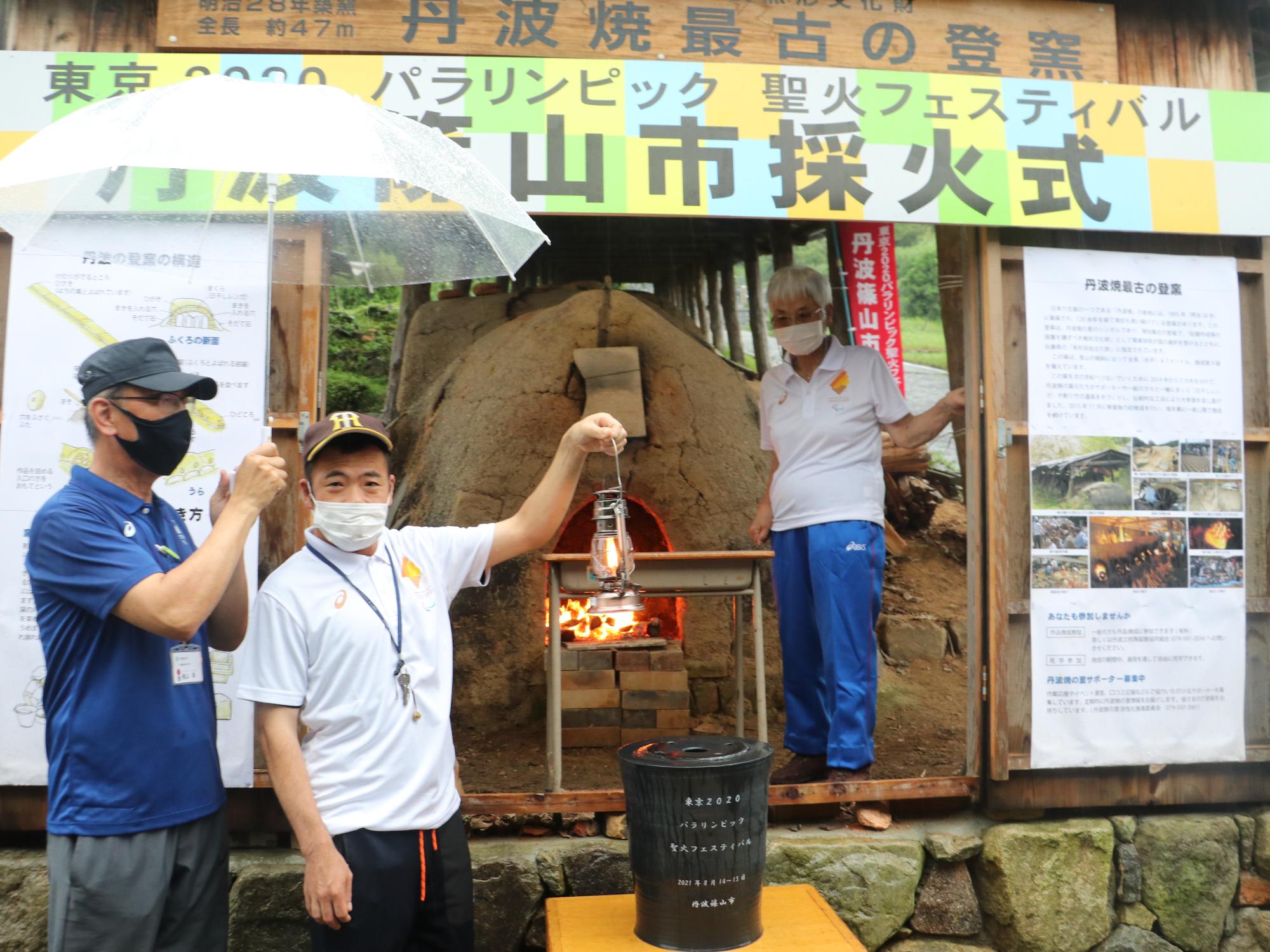 聖火が採火されたランタンを男性が掲げている